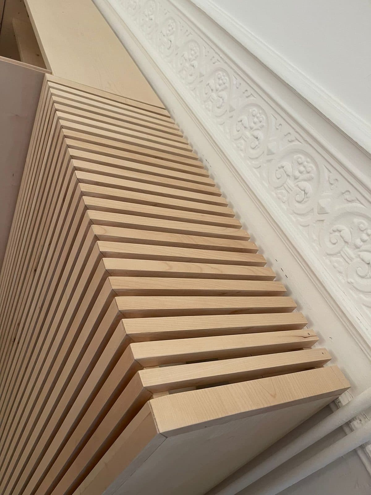 Le même cache-radiateur vu du dessus, contre un soubassement à relief ornemental