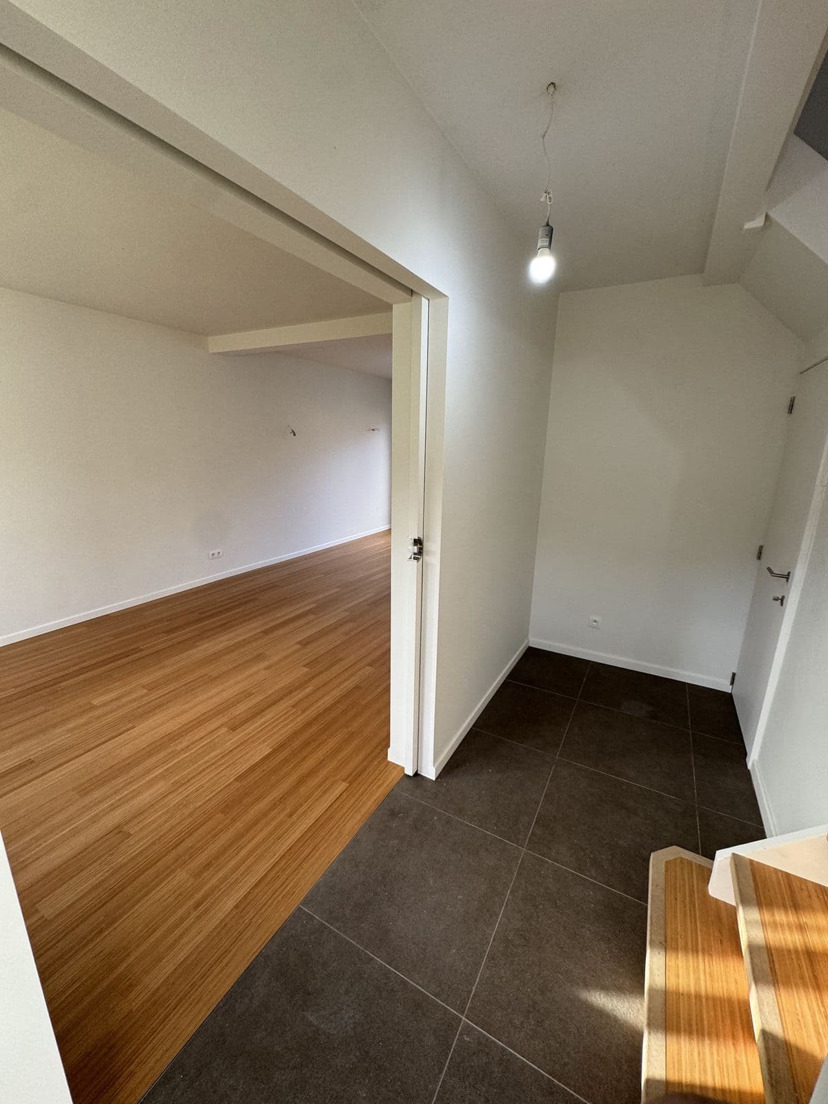 Passage entre deux pièces, parquet d’un côté, carrelage gris foncé de l’autre