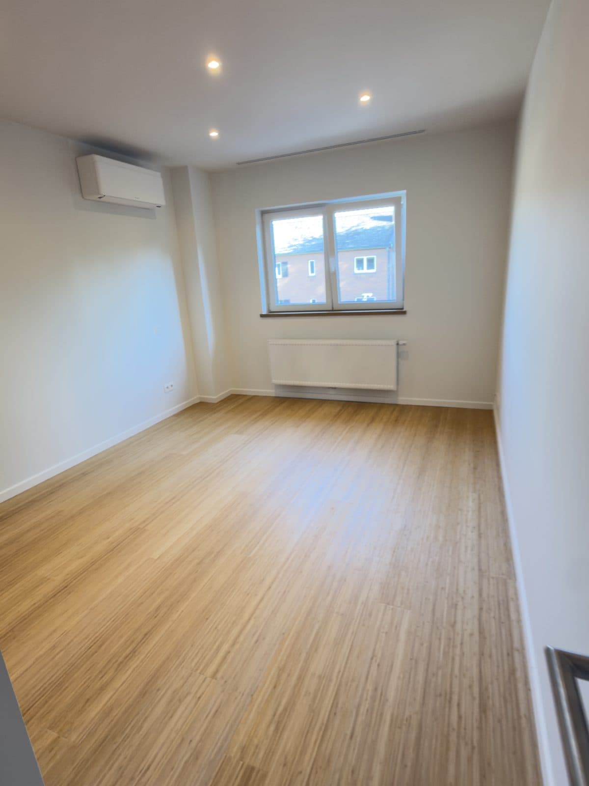 Chambre avec fenêtre à deux vantaux, radiateur, climatiseur mural et parquet à lames fines