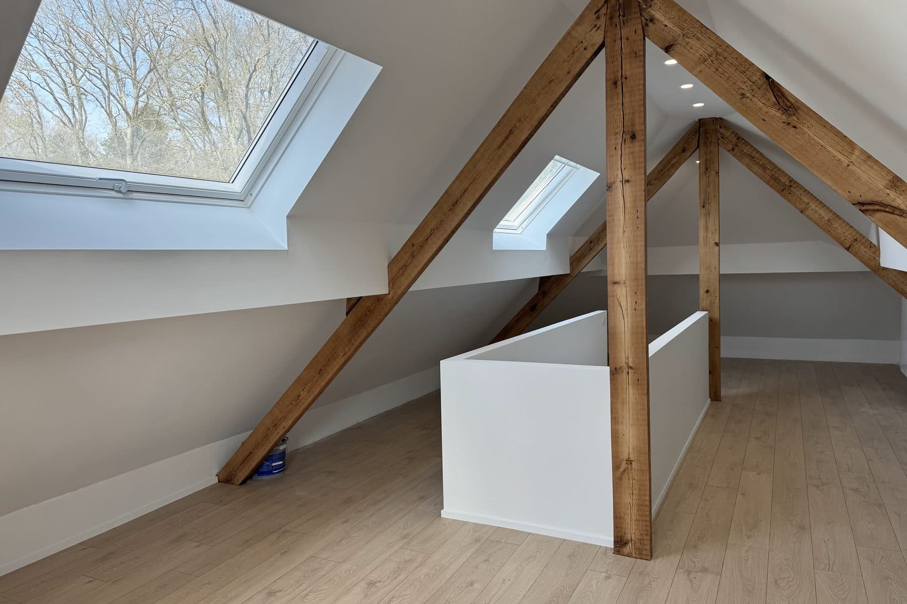 Combles aménagés : fermes en chêne apparentes, deux fenêtres de toit, garde-corps blanc de la trémie, sol aspect chêne clair