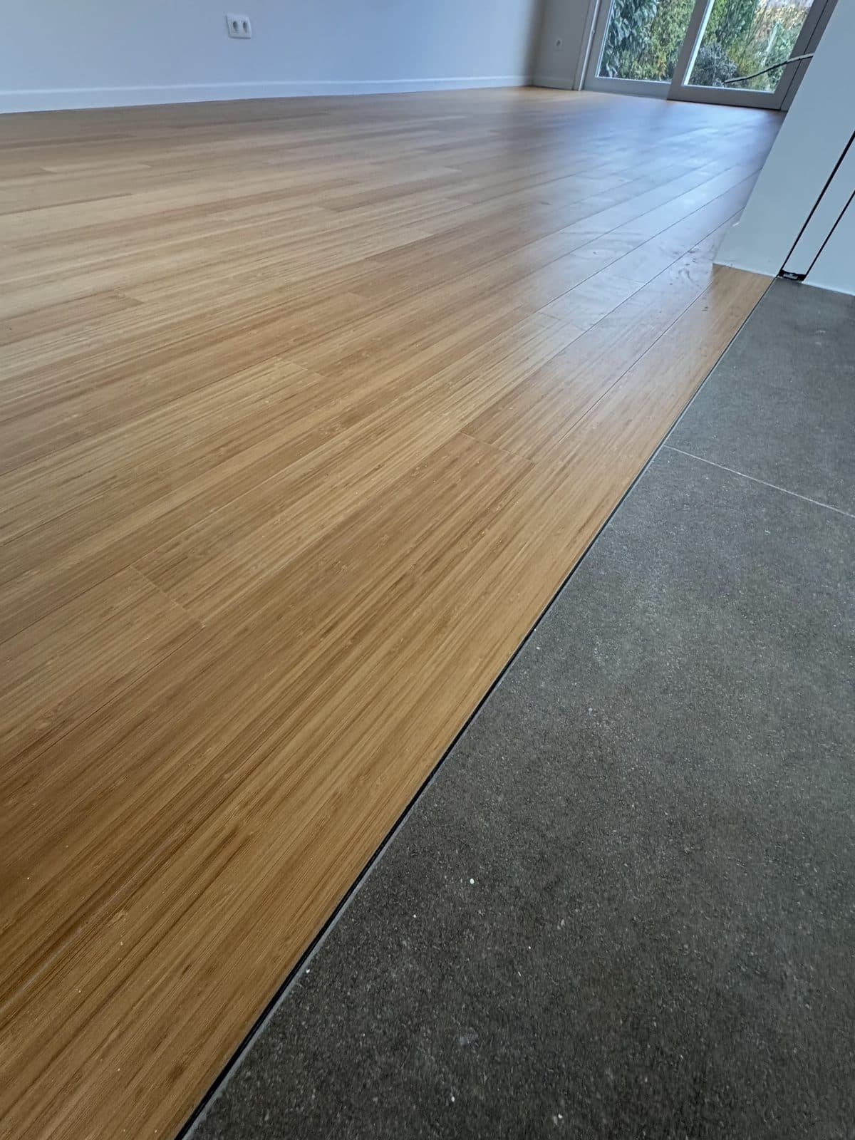 O assoalho encontra o porcelanato cinza-escuro ao longo de um perfil metálico fino