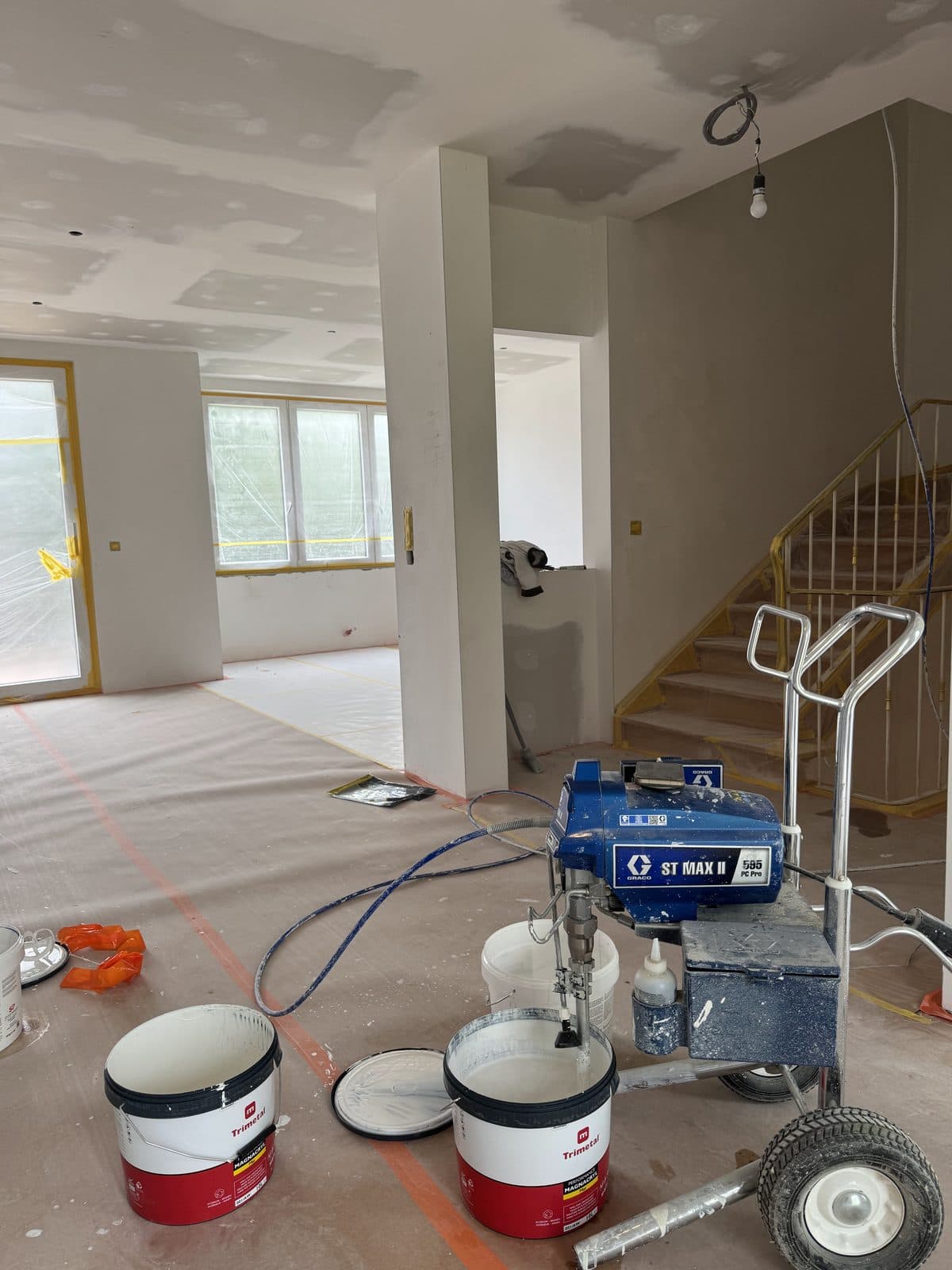 Étape peinture : sols protégés, pompe à peinture et seaux, escalier au garde-corps protégé