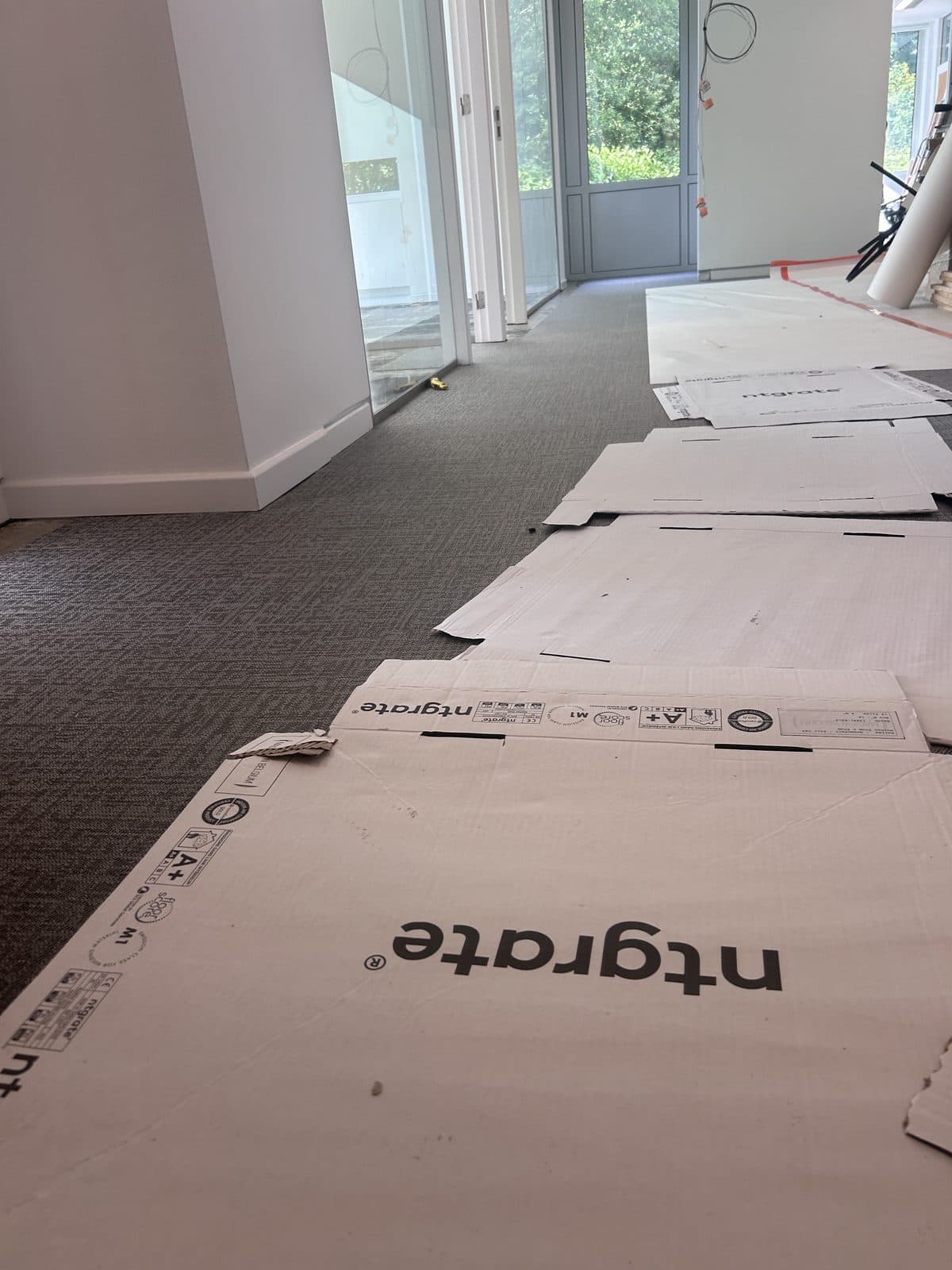Le couloir pendant la pose, cartons à plat au sol, cloisons vitrées