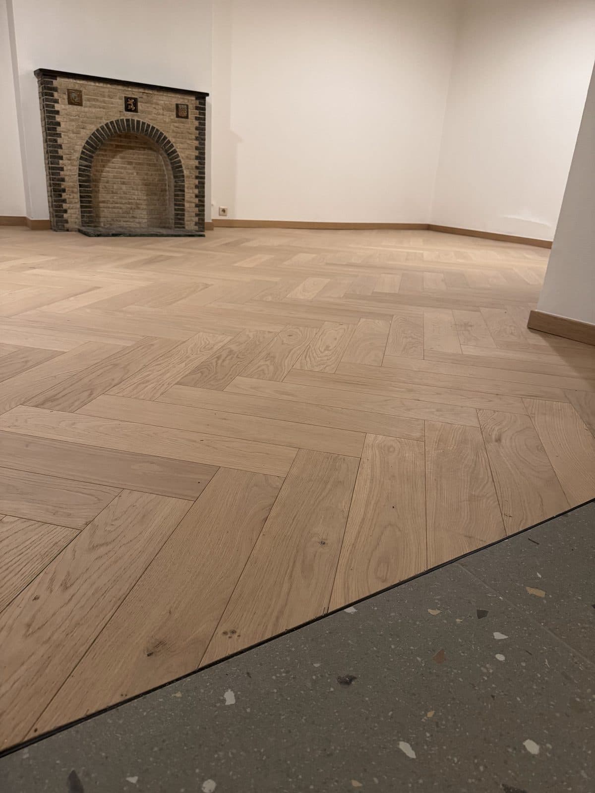 Parquet à bâtons rompus terminé devant une cheminée en briques à arc