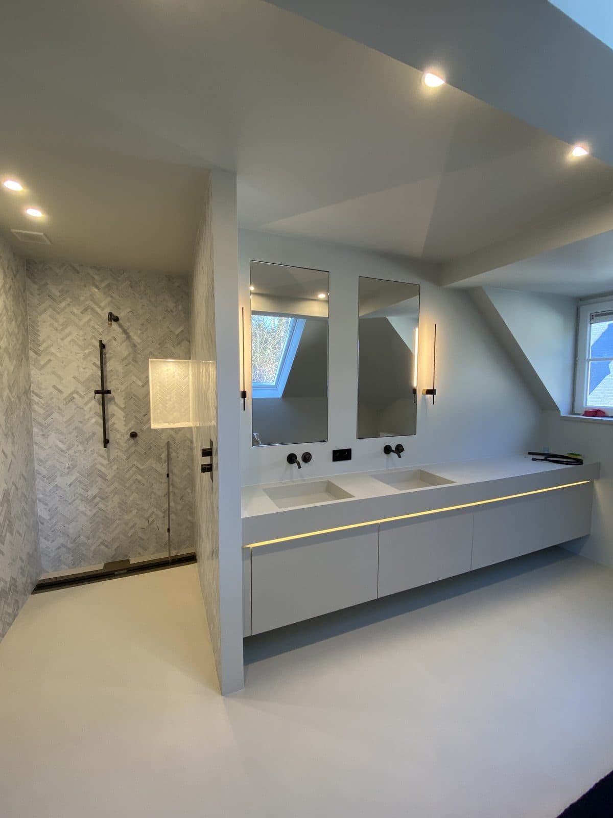 Salle de bain sous pente : douche à l’italienne en mosaïque de marbre à chevrons, robinetterie noire, double vasque blanche suspendue