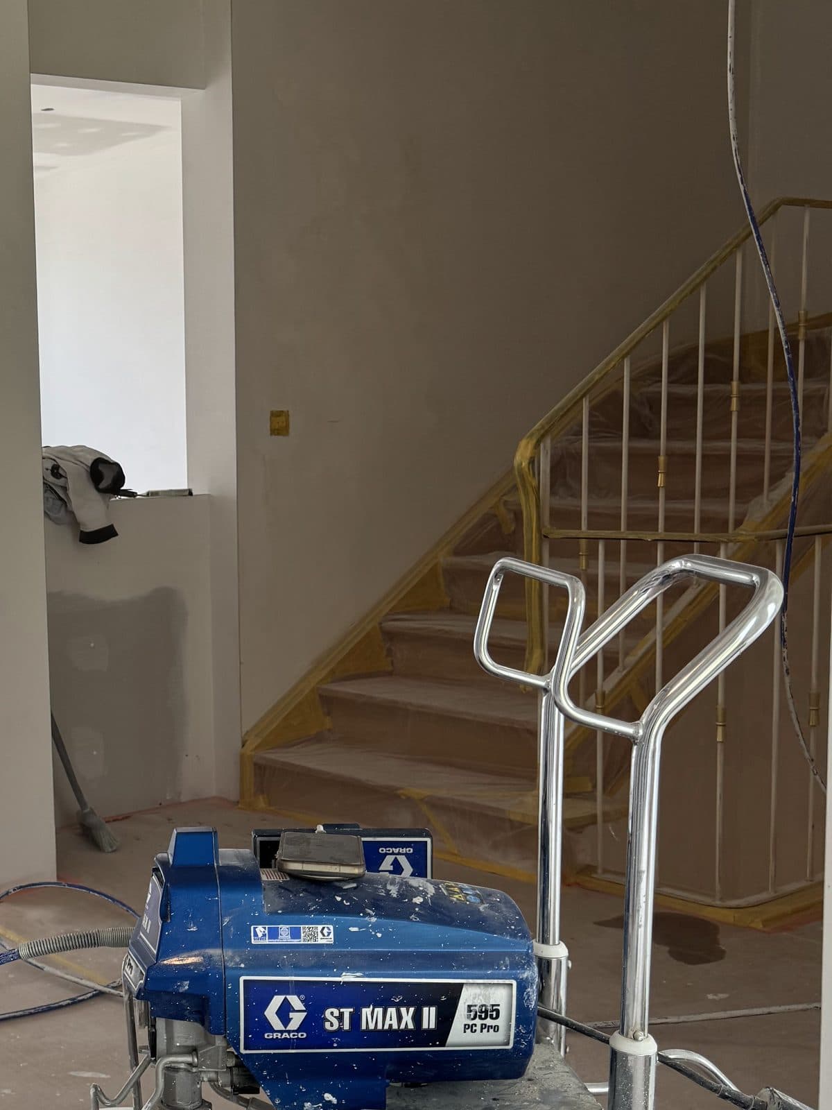 L’escalier pendant la peinture, garde-corps entouré de ruban jaune, sols protégés